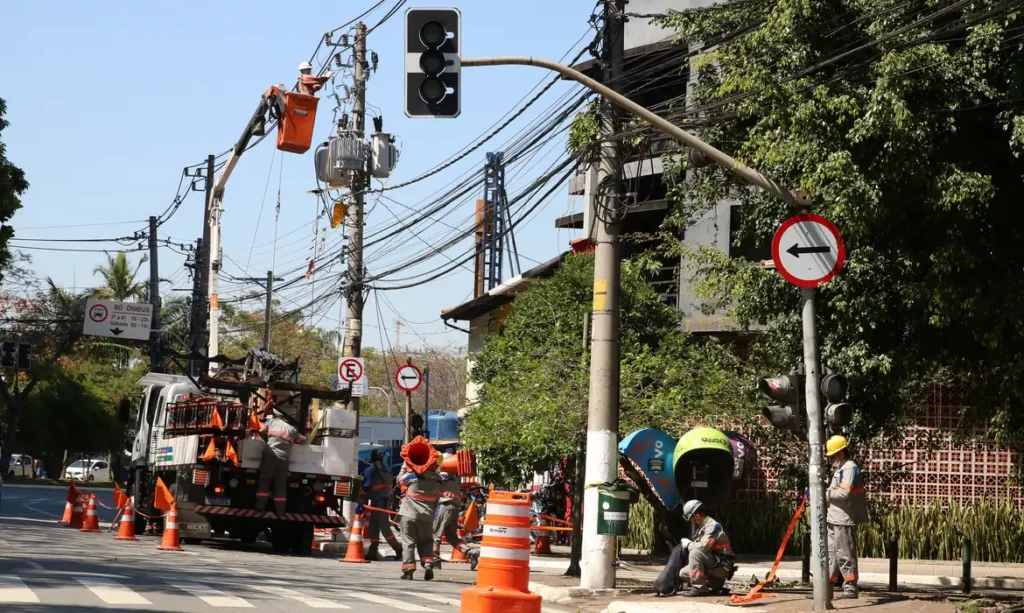 Funcionários da Enel fazem manutenção em poste de energia elétrica no bairro de Pinheiros.