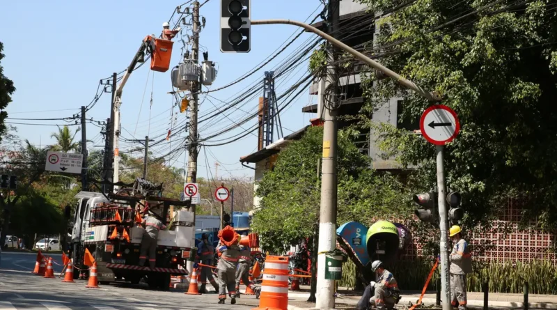 Funcionários da Enel fazem manutenção em poste de energia elétrica no bairro de Pinheiros.