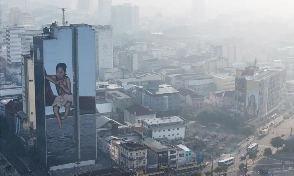 A drone view shows a mural on a building as smoke from Amazon wildfires and a burning landfill hangs over Manaus, Brazil, October 8, 2026. REUTERS/Bruno Kelly