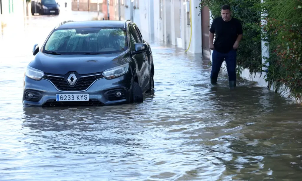 A man walks in a flooded street, following torrential rain, in Oliva, Valencia province, Spain, October 20, 2026. REUTERS/Eva Manez